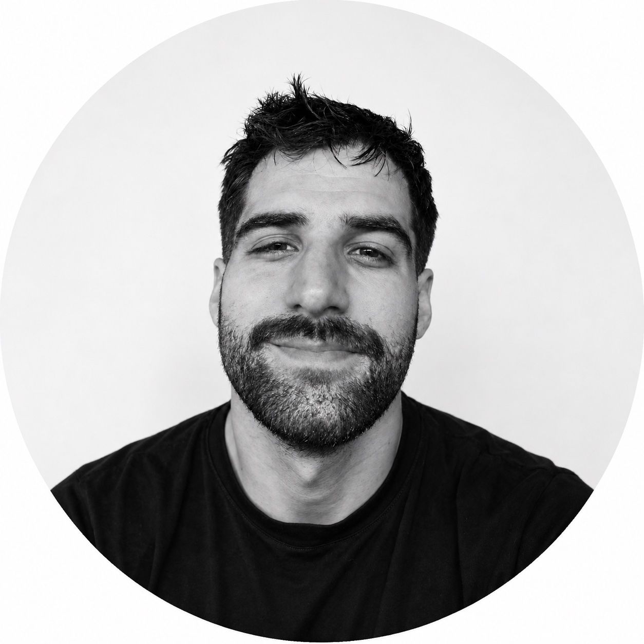 Black and white headshot of a smiling man with dark hair and a beard.