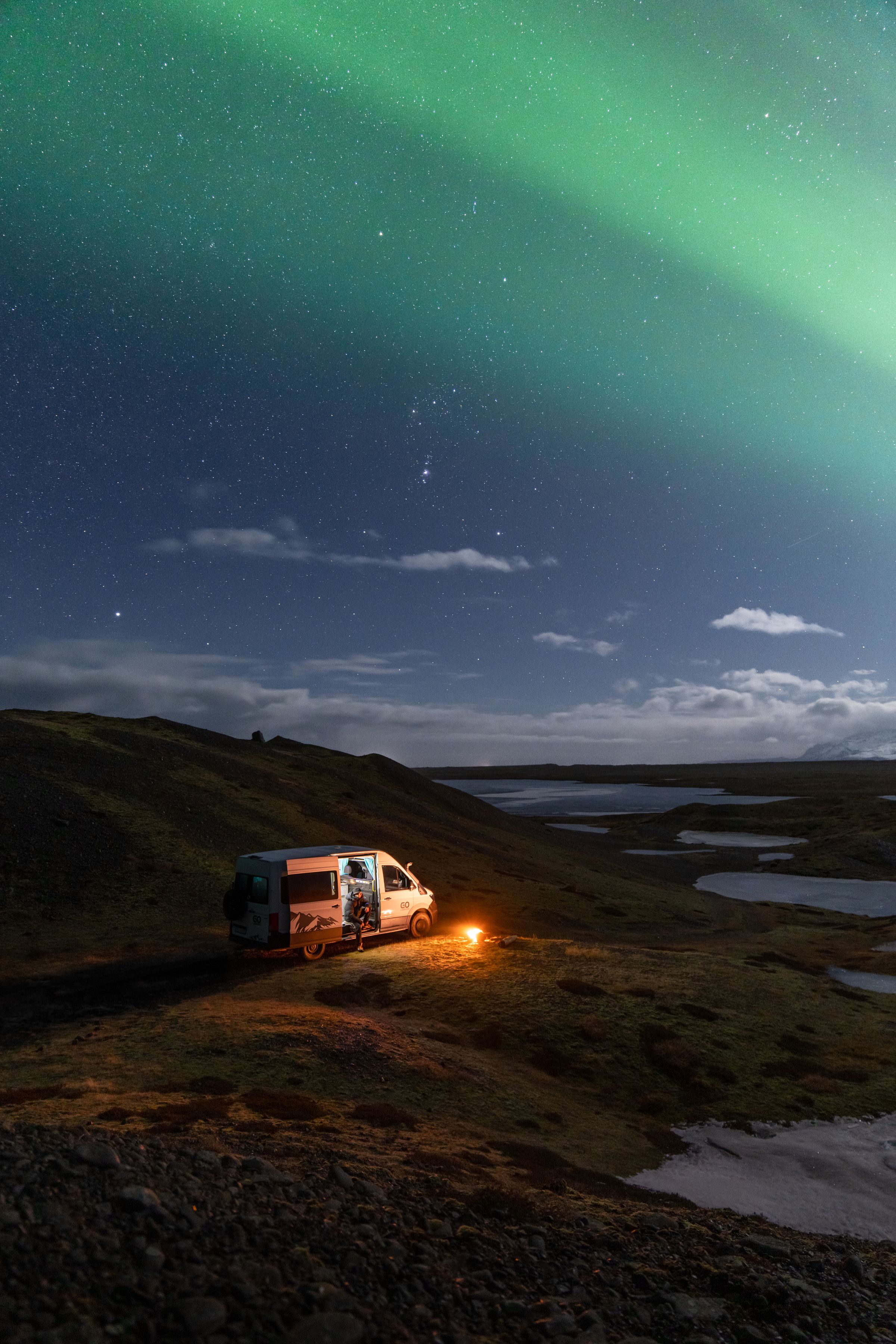 Una autocaravana 4x4 para 3 personas en una ladera por la noche, sobre un lago, alquiler de autocaravanas en Islandia