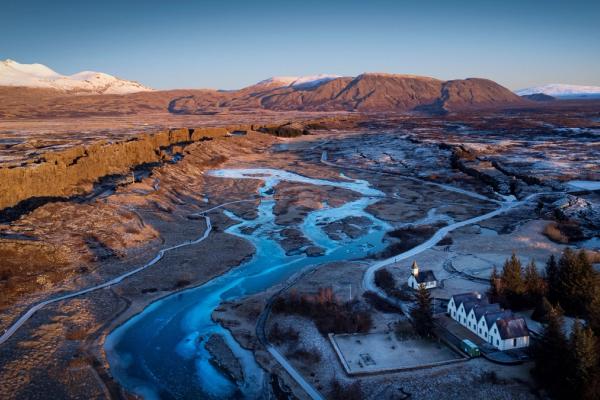 an aerial view of a river flowing through a valley with mountains in the background .