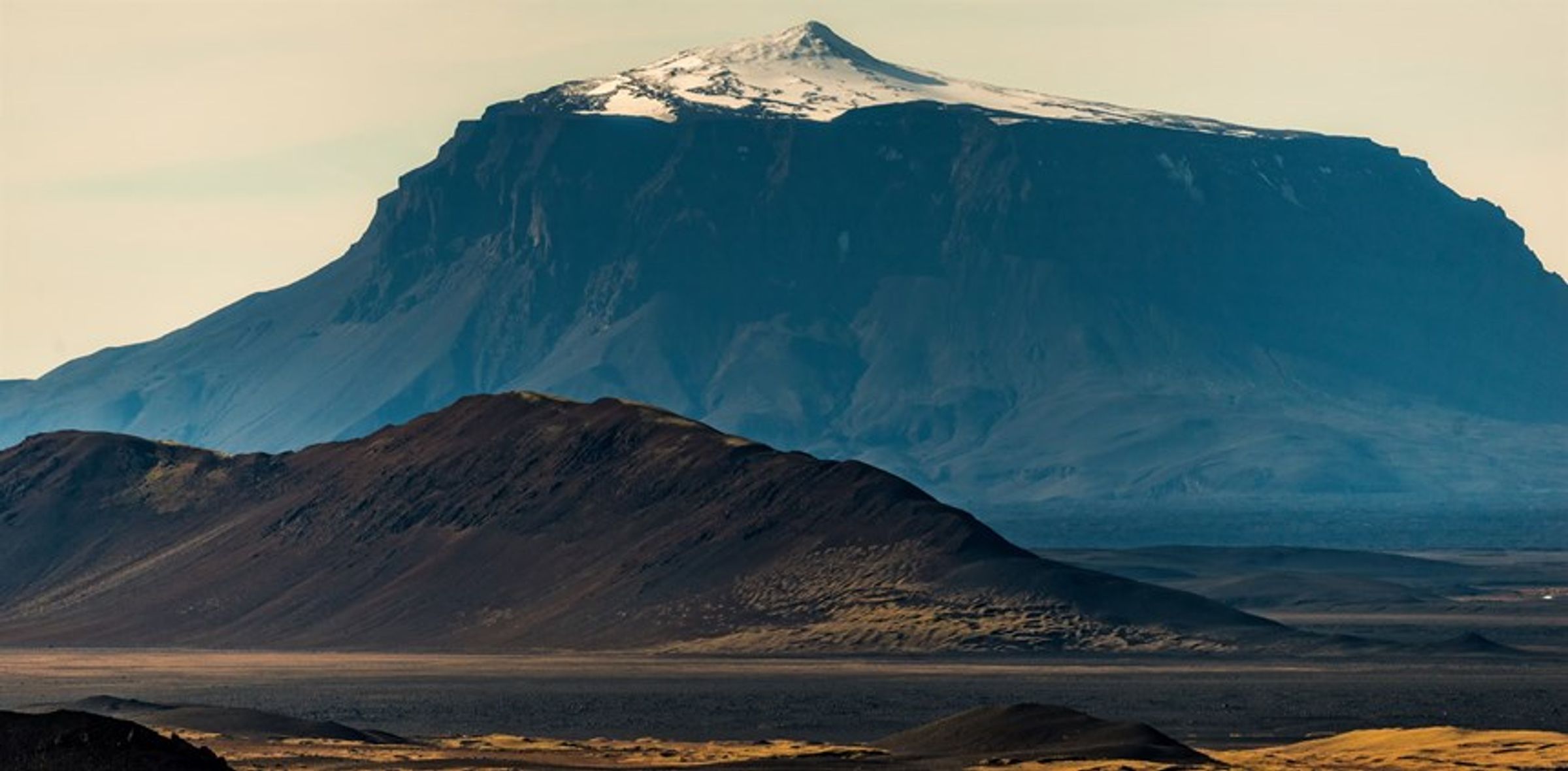 une grande montagne couverte de neige est entourée de montagnes plus petites, Herðubreiðarlindir