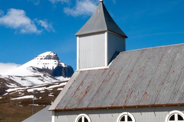 a church with a cross on top of it and a mountain in the background