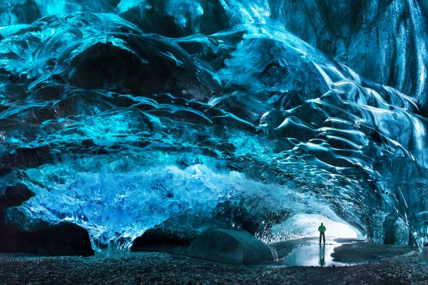 a man is standing inside of an ice cave .