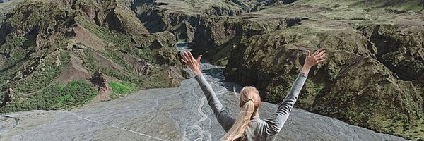 Mujer con los brazos arriba delante de unas montañas