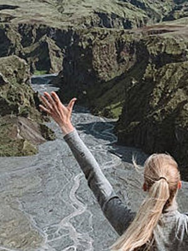 Mujer con los brazos arriba delante de unas montañas