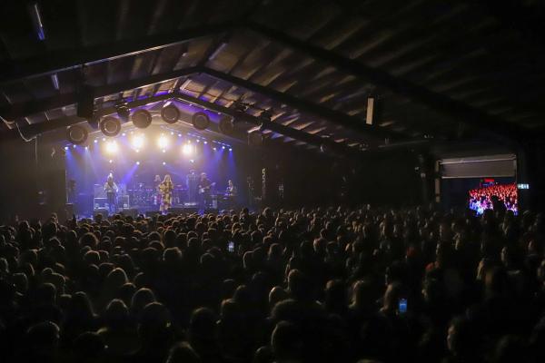a large crowd of people are watching a band on stage at a concert .