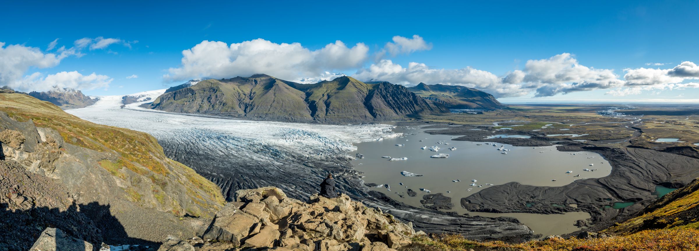 una vista panorámica de un glaciar rodeado de montañas y un lago .
