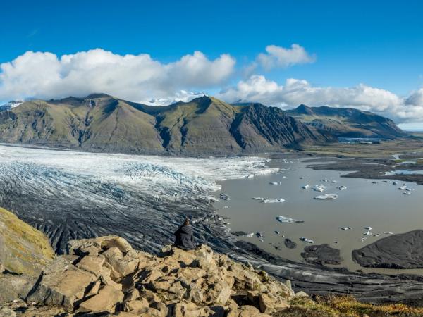 una vista panorámica de un glaciar rodeado de montañas y un lago .