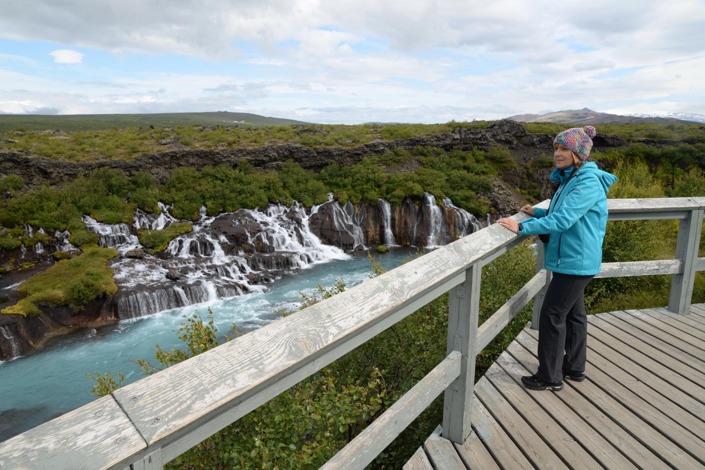 Mujer viendo Hraunfossar desde una plataforma