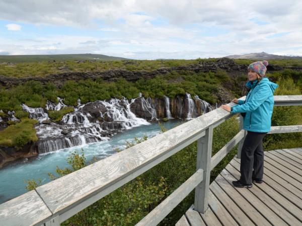 Mujer viendo Hraunfossar desde una plataforma