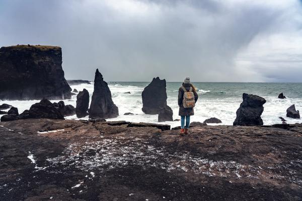 a woman is standing on a rocky cliff overlooking the ocean .