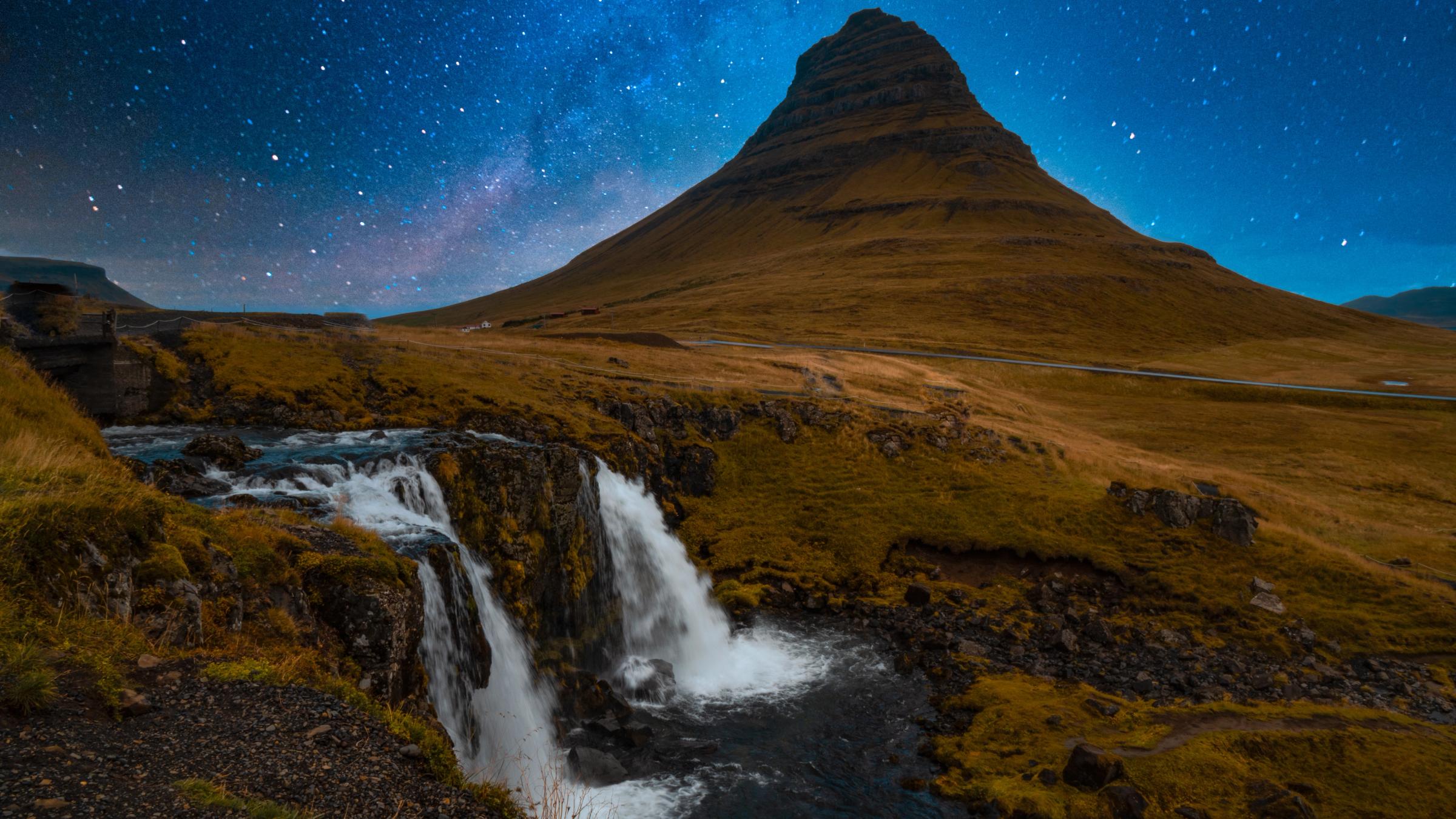 there is a waterfall in the foreground and a mountain in the background .
