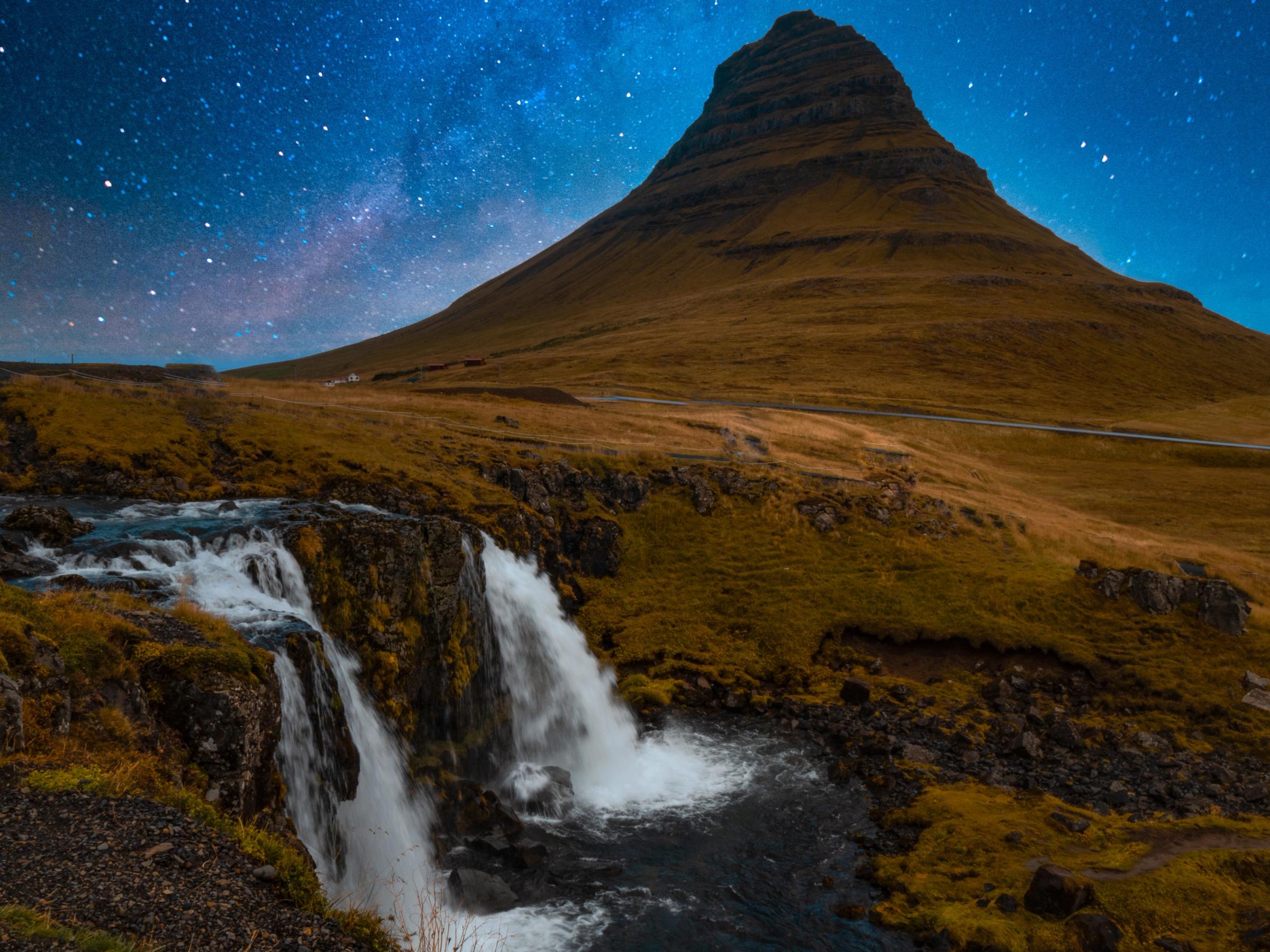 there is a waterfall in the foreground and a mountain in the background .