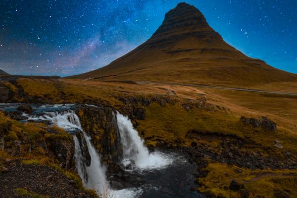 there is a waterfall in the foreground and a mountain in the background .