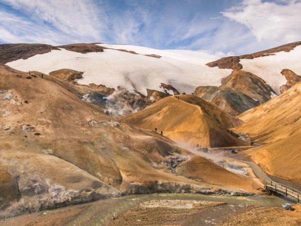 a group of people standing on top of a mountain next to a river .