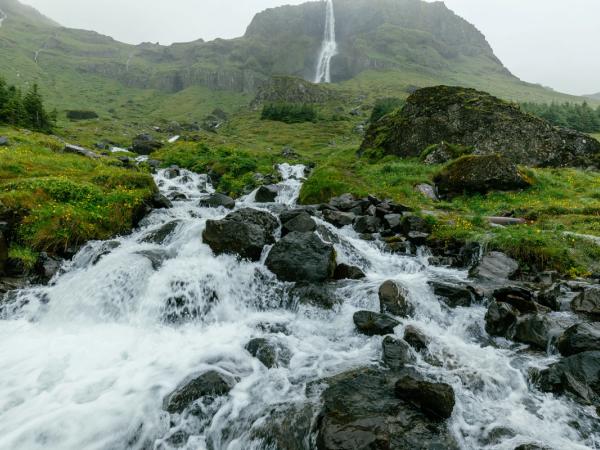 a small waterfall in the middle of a mountain surrounded by rocks and grass .