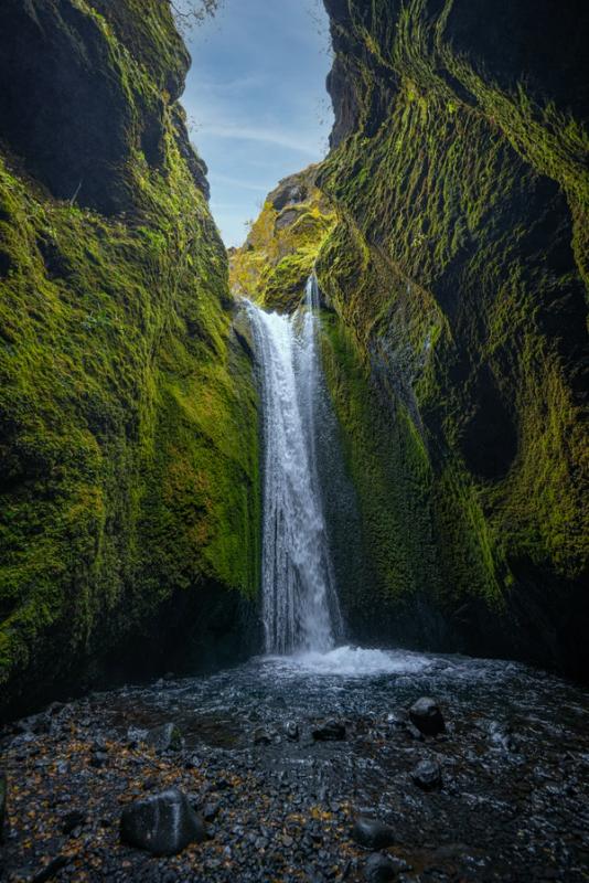 a waterfall in the middle of a canyon surrounded by green moss at Nauthúsagil in iceland.