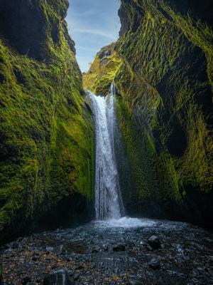 a waterfall in the middle of a canyon surrounded by green moss at Nauthúsagil in iceland.