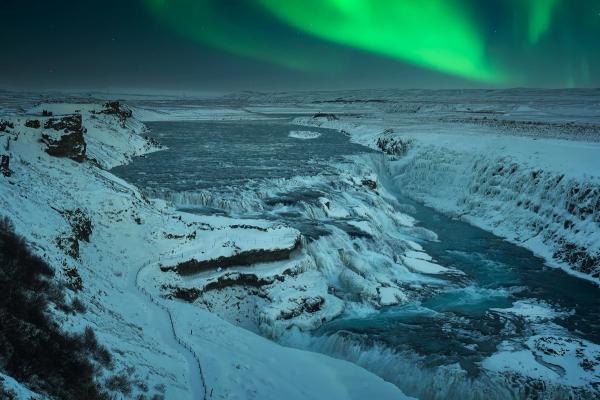 the aurora borealis is shining over a waterfall in iceland.
