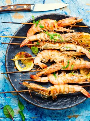 grilled shrimp on skewers on a plate on a blue table .