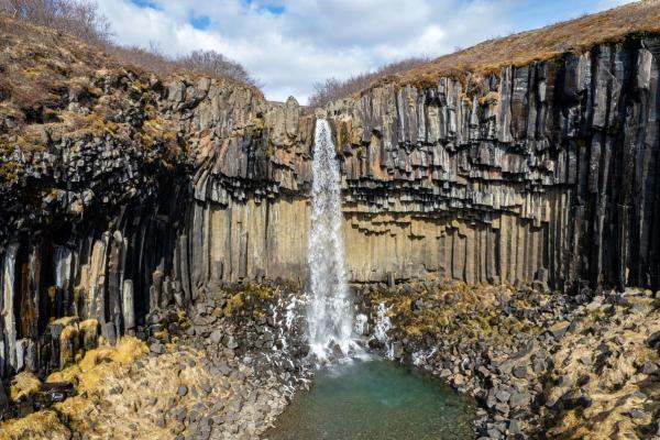 an aerial view of a waterfall in a canyon surrounded by rocks .