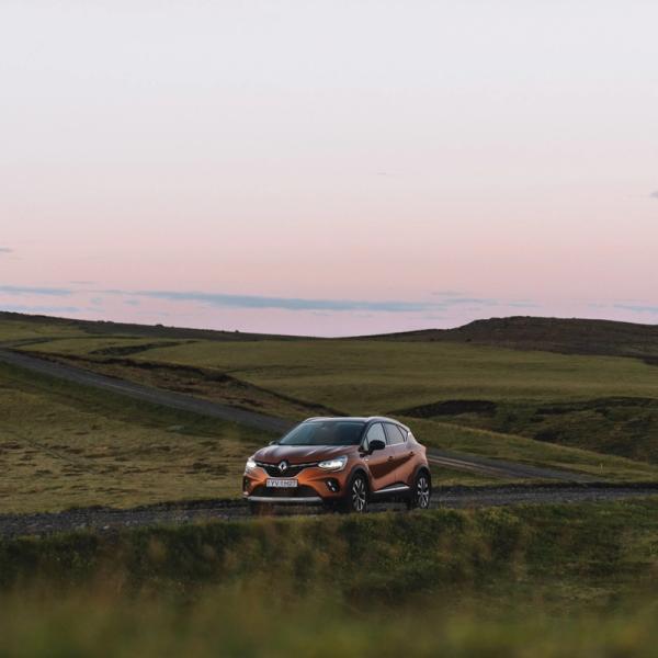 a car is driving down a road in the middle of a field .