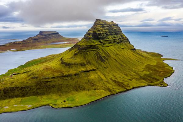 una montaña cubierta de hierba verde rodeada de agua