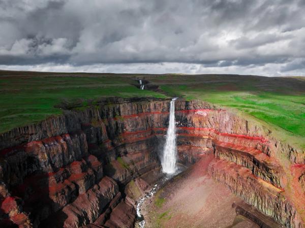 an aerial view of a waterfall in the middle of a canyon .