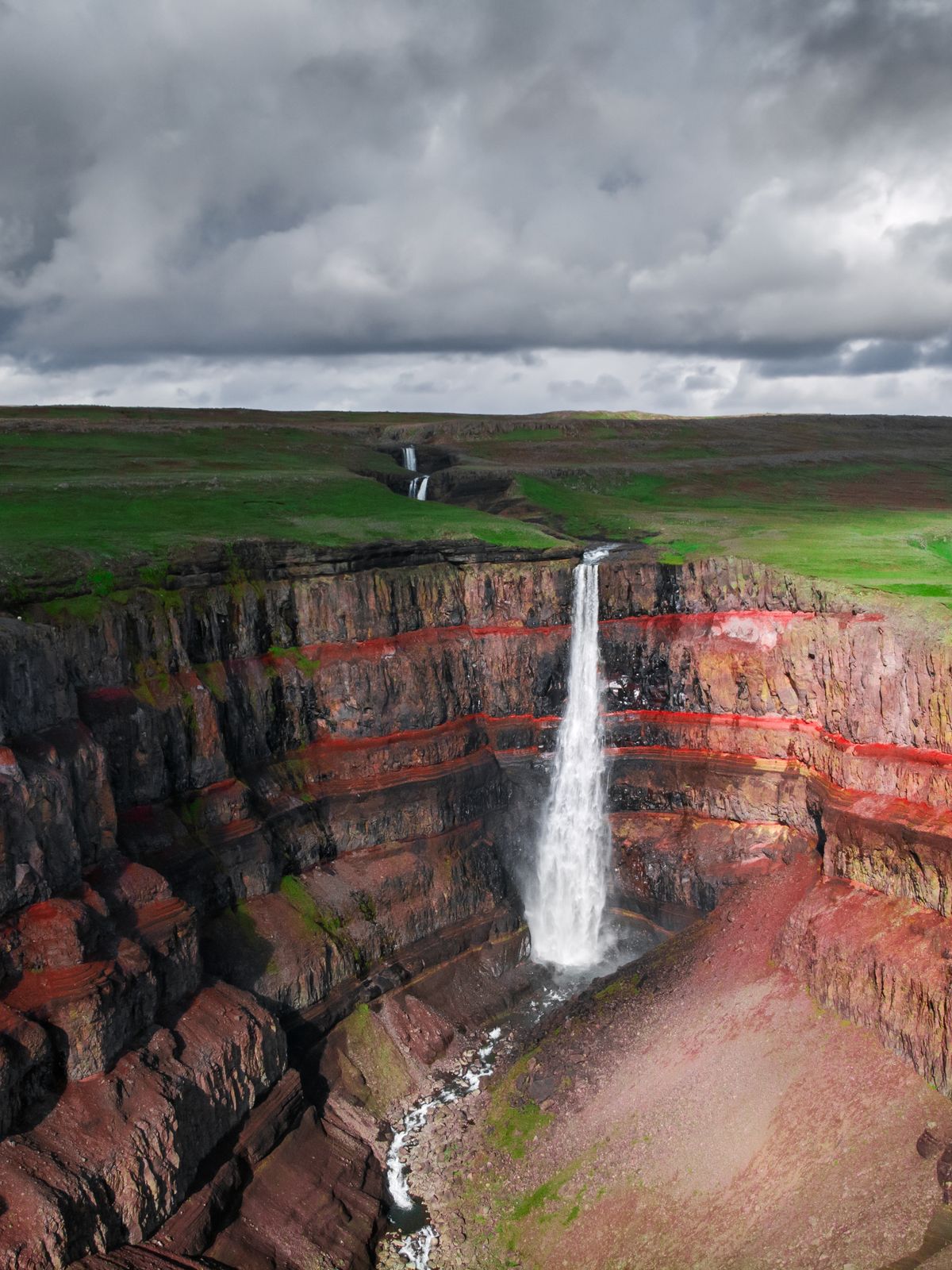 an aerial view of a waterfall in the middle of a canyon .