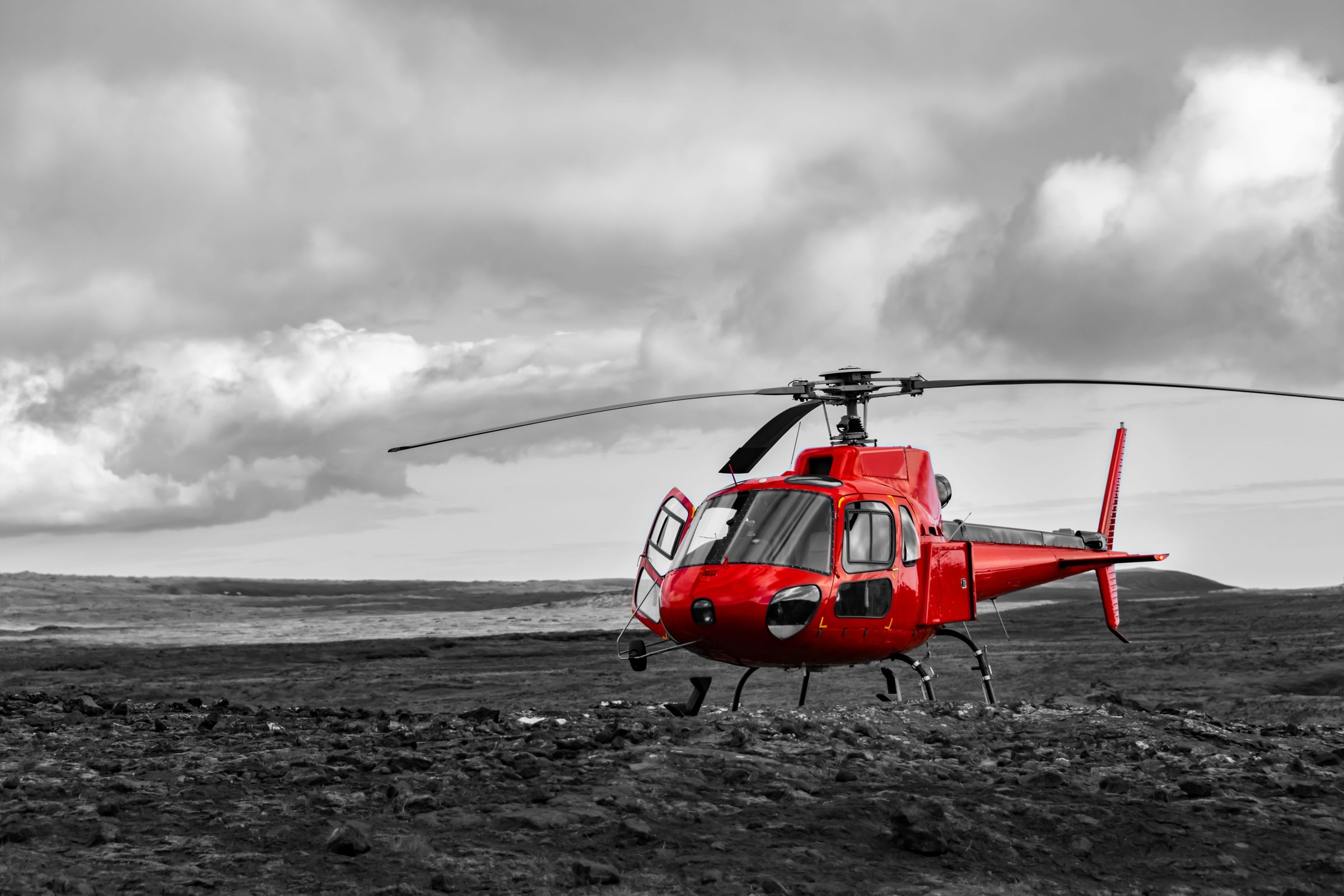 a red helicopter is parked in a black and white photo .
