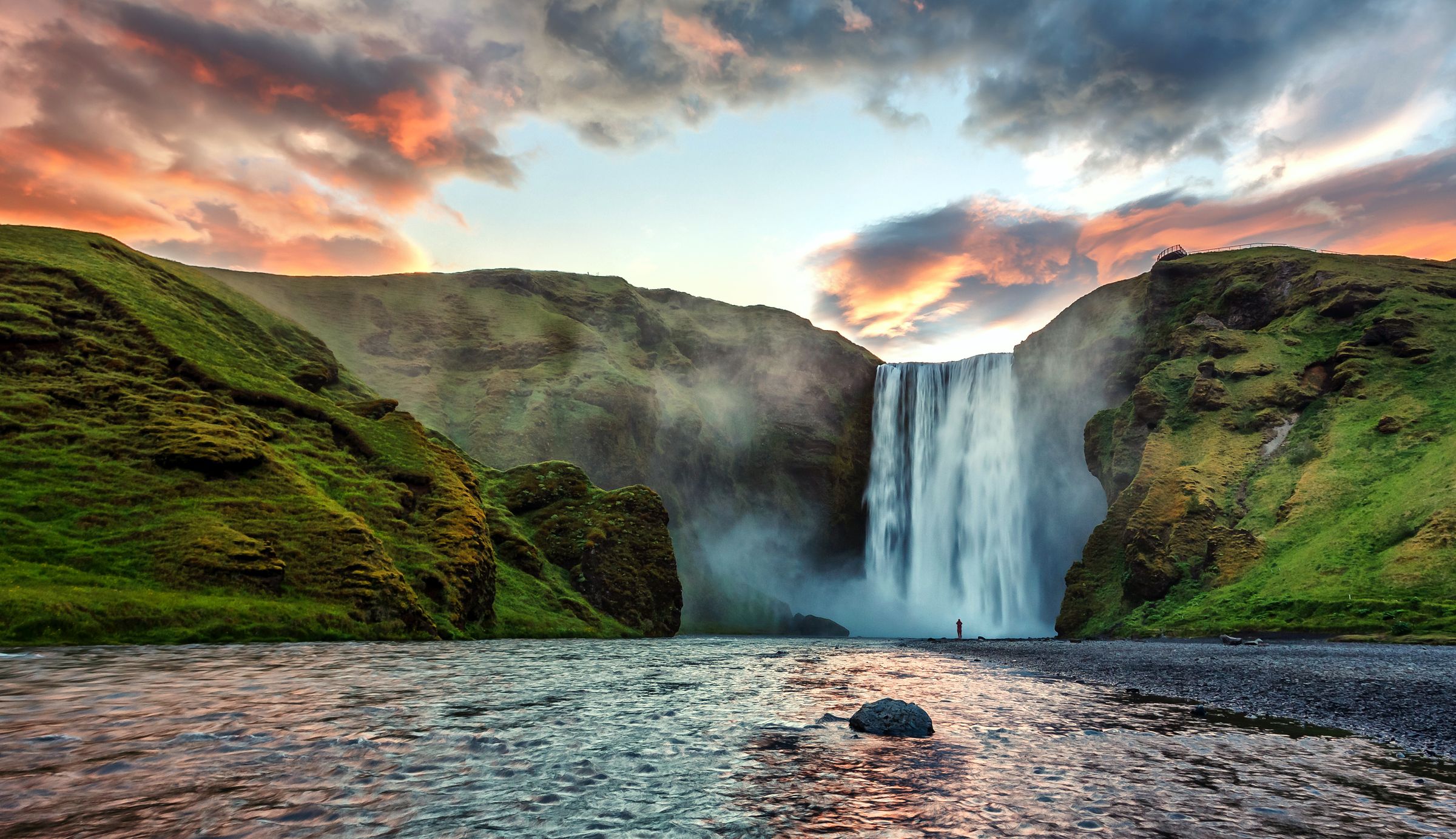 a waterfall in the middle of a river surrounded by mountains at skógafoss in iceland.
