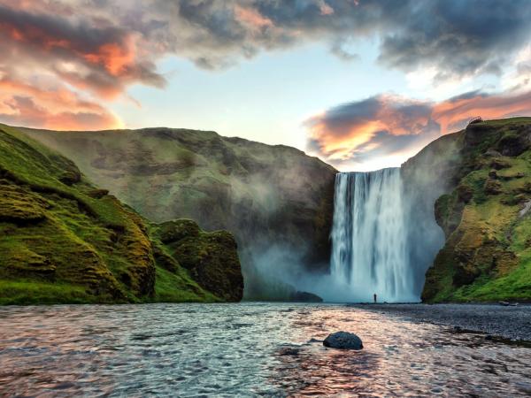 a waterfall in the middle of a river surrounded by mountains at skógafoss in iceland.