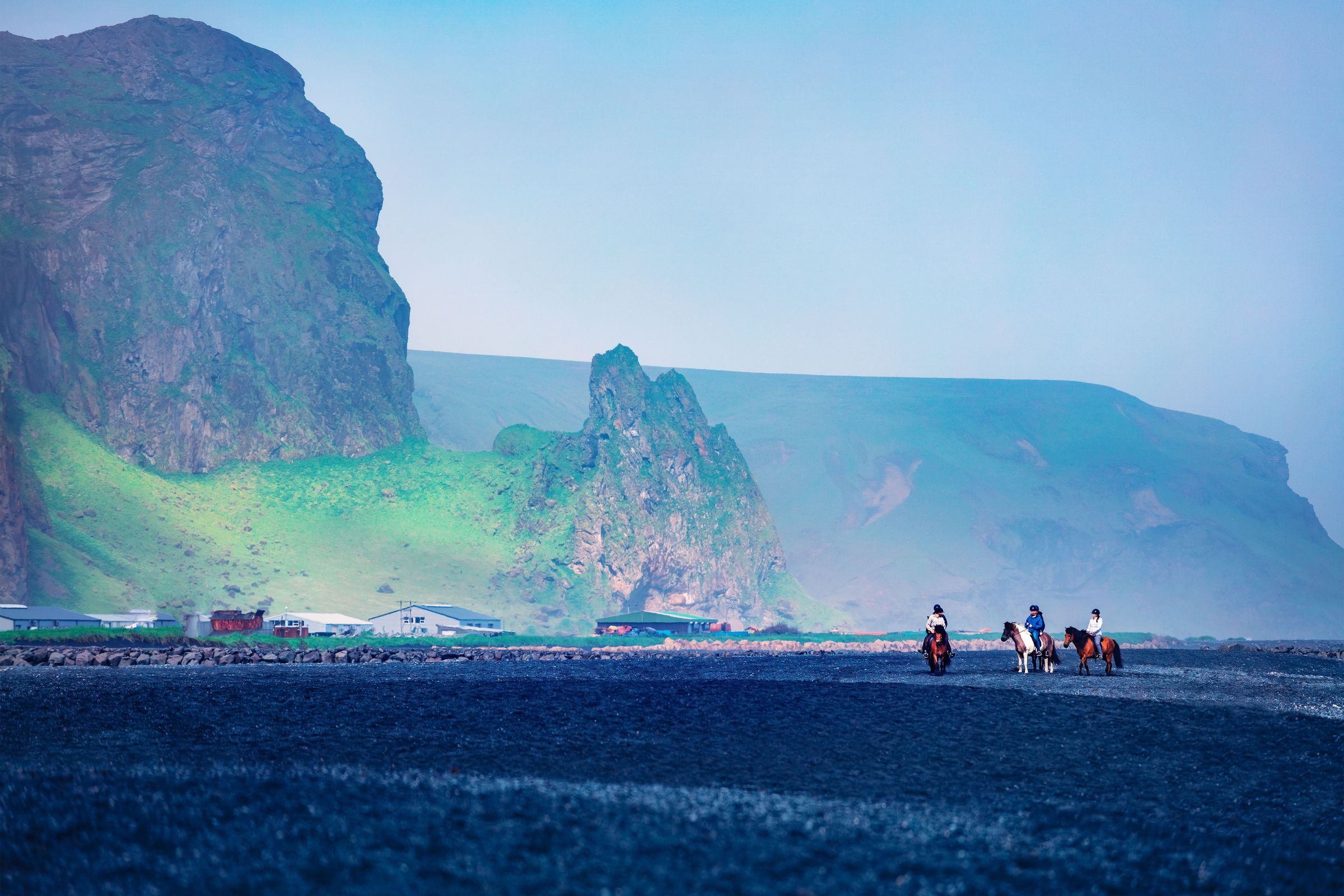 a group of people are riding horses on a beach .