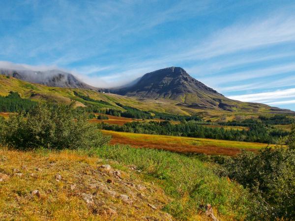 Rugged mountain landscape with colorful fields and low-lying clouds.