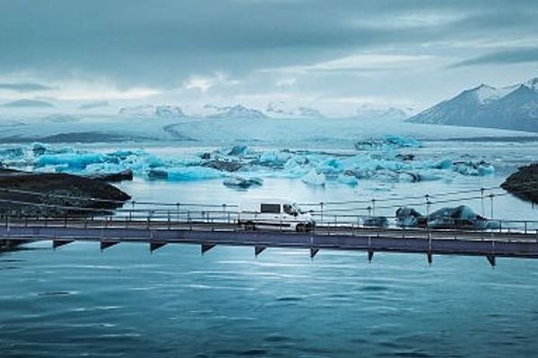 a truck is driving across a bridge over a body of water .