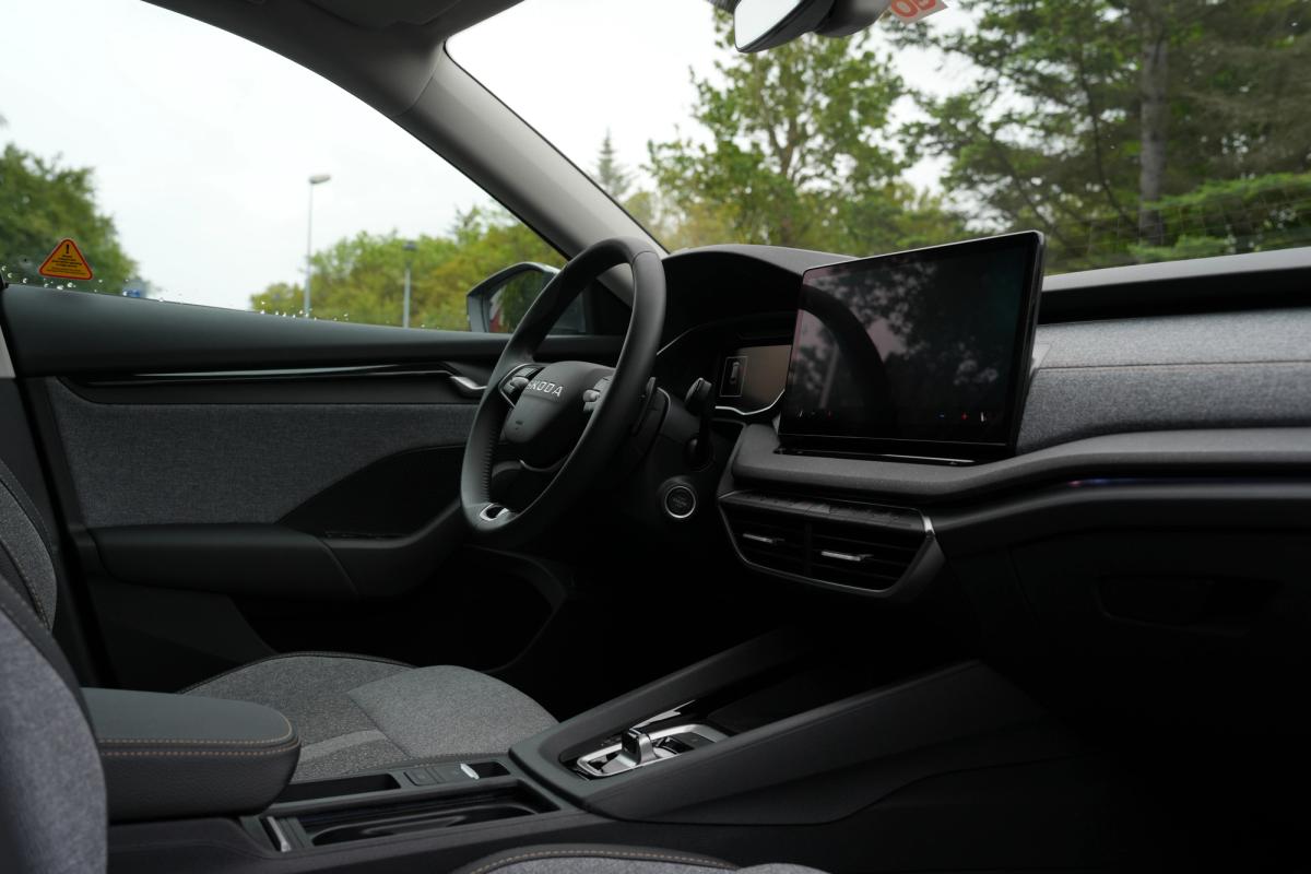 Innanrými Skoda Octavia-stationbíls með útsýni yfir mælaborð og upplýsinga- og afþreyingarskjá, með tré fyrir utan