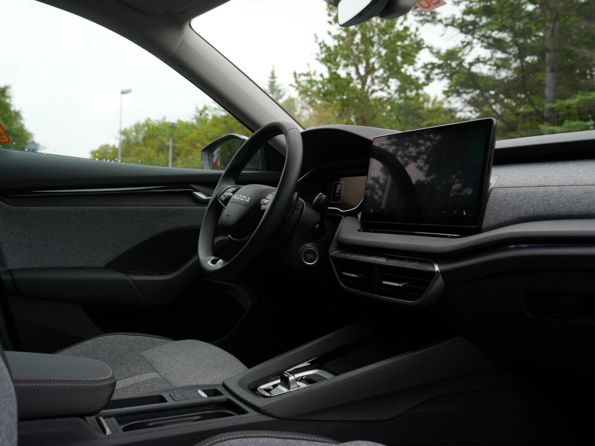 Víðmynd af innanrými Octavia-stationbílsins Innanrými Skoda Octavia-stationbíls með útsýni yfir mælaborð og upplýsinga- og afþreyingarskjá, með tré fyrir utan