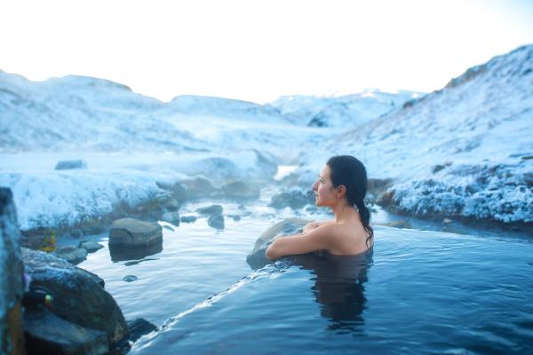 a woman is taking a bath in a hot spring in the mountains in icelajd.