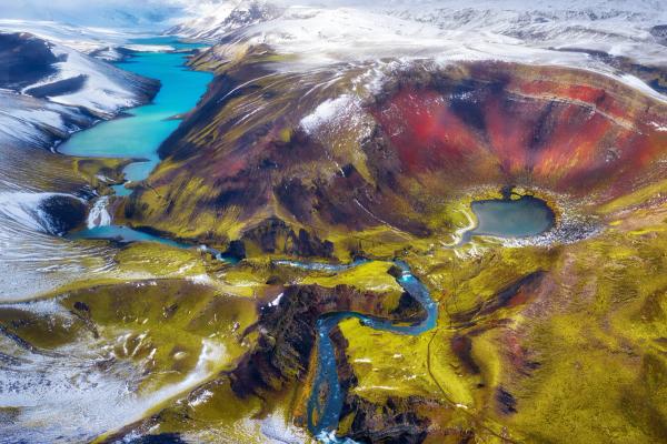 an aerial view of a colorful mountain landscape with a river running through it in iceland. .