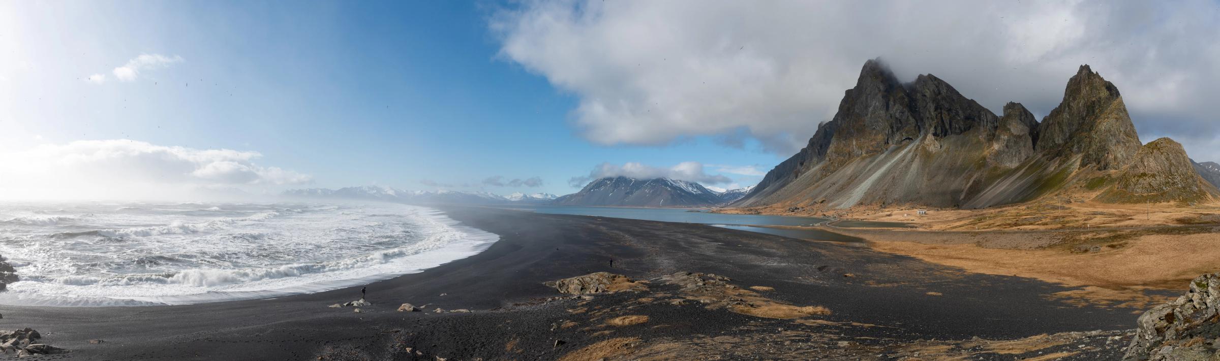 una vista panorámica de una playa de arena negra con montañas en el fondo .