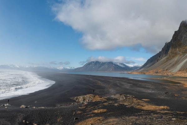 a panoramic view of a black sand beach with mountains in the background .