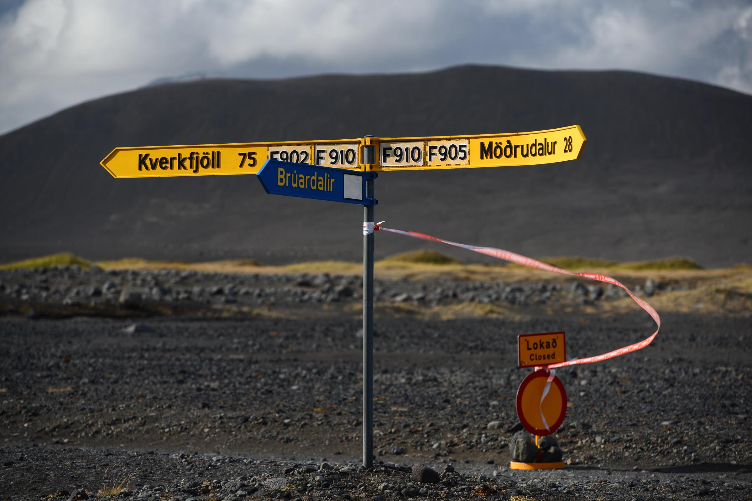 En un paisaje oscuro y desolado, un poste indicador señala hacia Kverkfjöll, Brúardalir y Möðrudalur, con un cartel de "Cerrado" y una cinta roja que bloquea uno de los caminos.