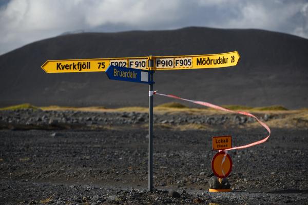 En un paisaje oscuro y desolado, un poste indicador señala hacia Kverkfjöll, Brúardalir y Möðrudalur, con un cartel de "Cerrado" y una cinta roja que bloquea uno de los caminos.