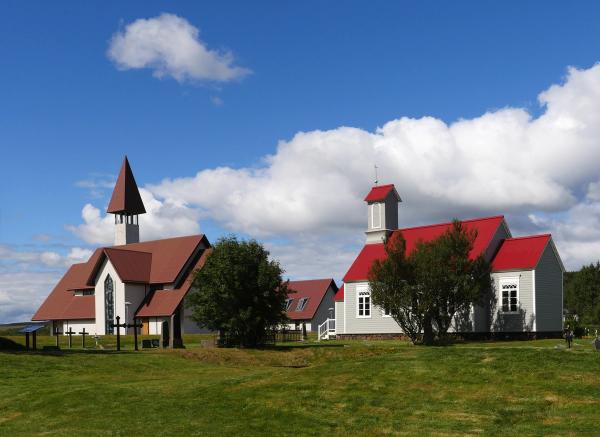 two churches with red roofs are sitting next to each other in a grassy field .