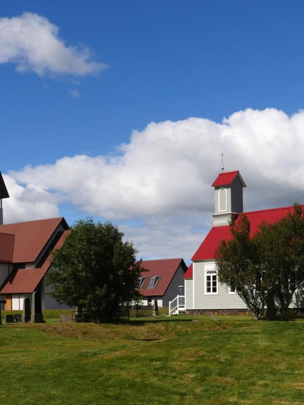dos iglesias con techos rojos están situadas una al lado de la otra en un campo verde.