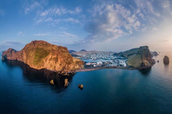 an aerial view of a Vestmannaeyjar island in the middle of the ocean at sunset .