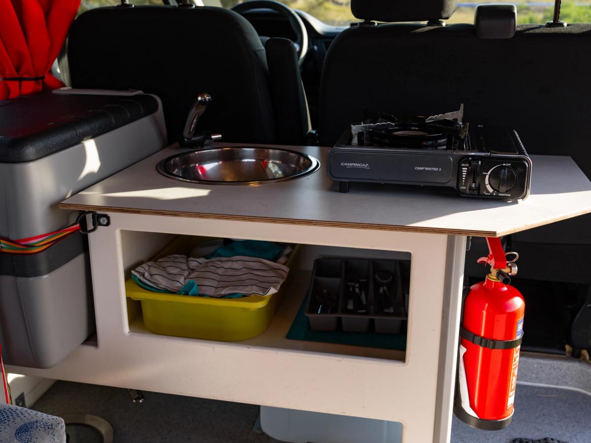 Cocina completa Mueble de cocina con fregadero y fogones, y un estante inferior con paños de cocina y una bandeja para cubiertos