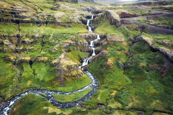 an aerial view of a waterfall in the middle of a lush green valley in klifbrekkufossar in iceland.