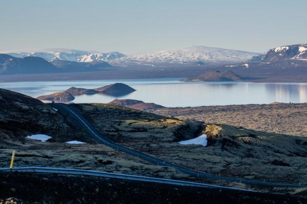 a road going through a mountainous area with a lake in the background .