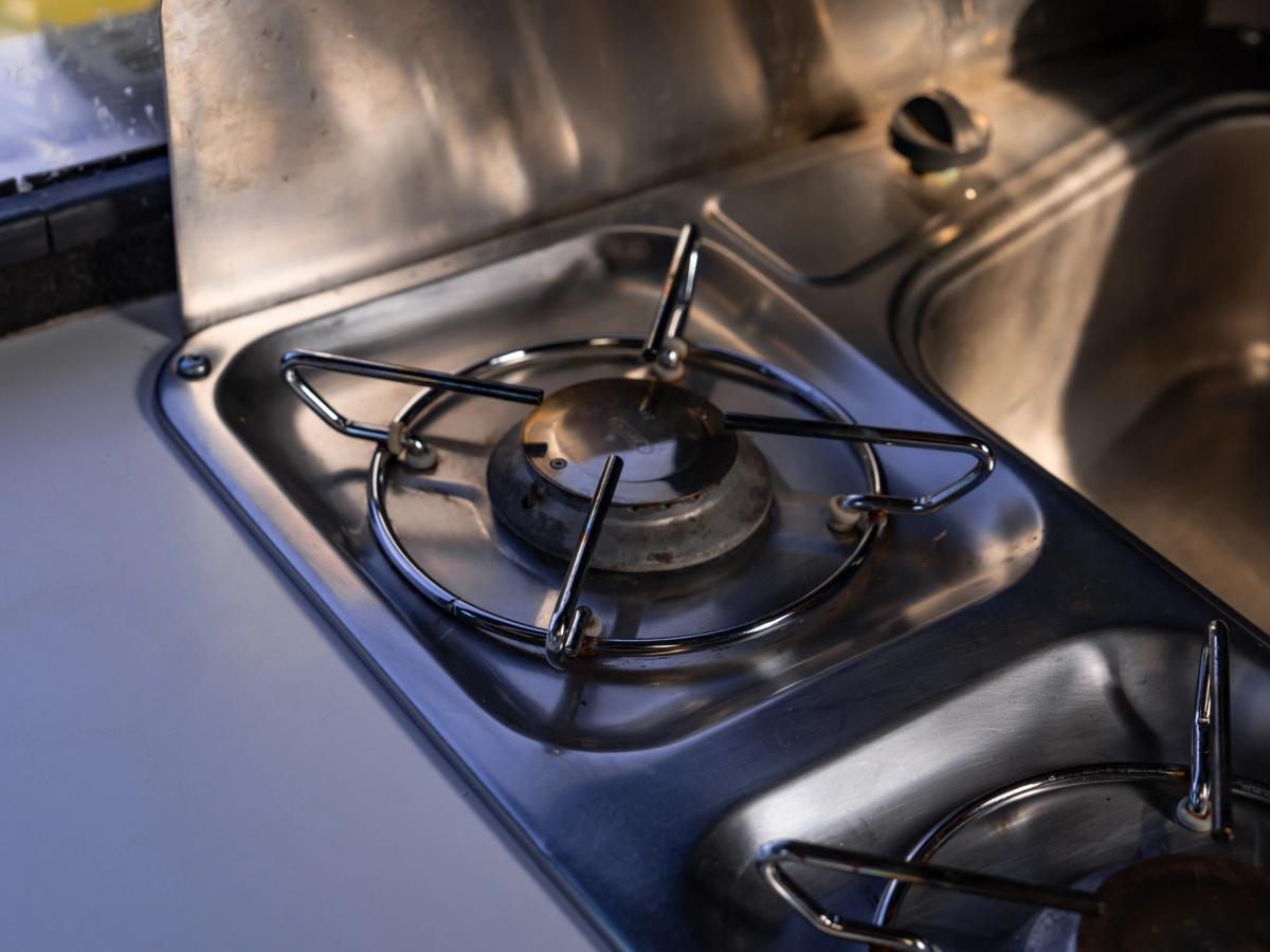 Gas Burner Close-Up Gas burners with metal pan supports set into the steel worktop beside the sink