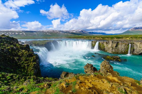 a waterfall is surrounded by rocks and mountains in the middle of a river .